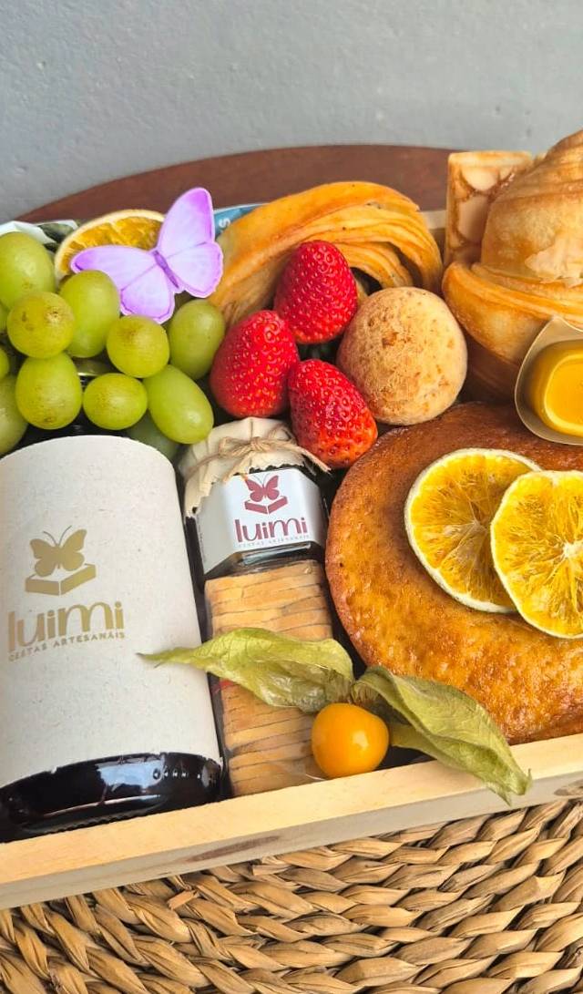 Detalhe dos itens de uma cesta de café da manhã: pães, frutas, doces e bebidas